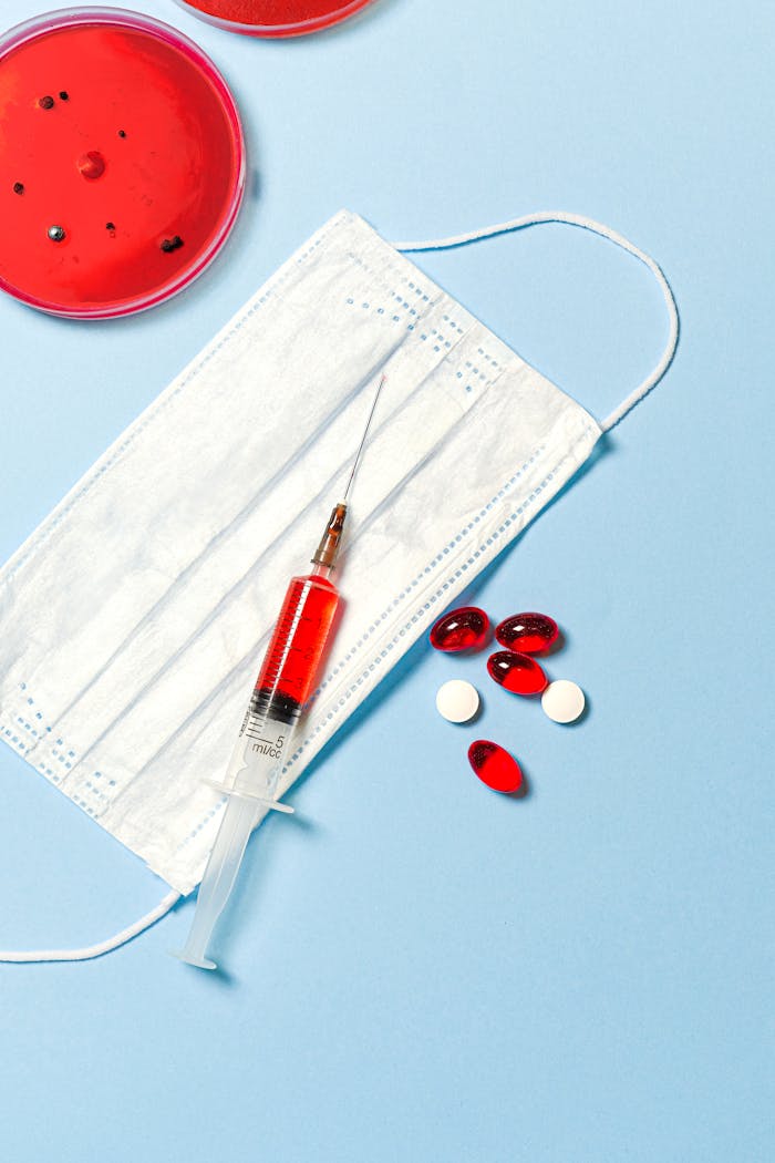 services-02 Face mask, syringe, and pills on a blue background, symbolizing healthcare and medical research.